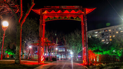 Chinese style red arch at night in the park with green lanterns and plants