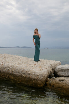 Fashion outdoor portrait of female model in long elegant green dress on the beach