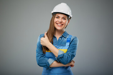Smiling woman builder or engineer in safety helmet showing thumb up. Isolated female portrait.