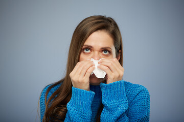 Woman blows his runny nose in napkin, looking up. Isolated female portrait healthcare and medical concept.