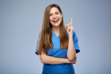 Smiling nurse woman pointing finger up. Isolated female portrait.