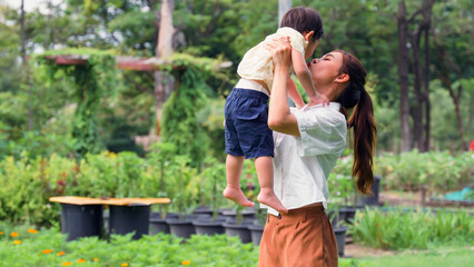 Mother kisses little son cheek while holding in her embrace.