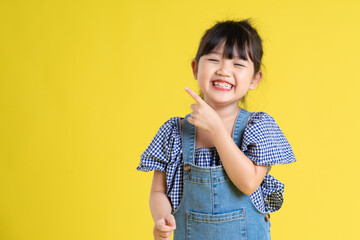 portrait of a beautiful asian girl, isolated on yellow background