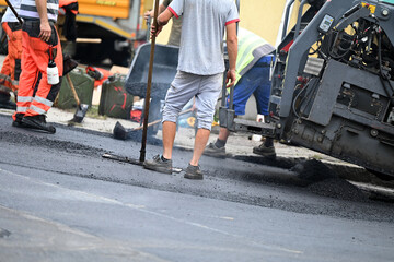 Feet of construction workers paving a road