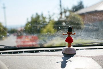 Hawaiian women toy decoration on the car dasboard, the sun coming in through the window