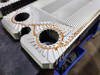 Applying glue on heat exchanger plate to attached gaskets in a factory, preparing heat exchanger plate pack.