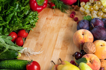 Juicy and ripe vegetables and fruits, berries around a wooden board.