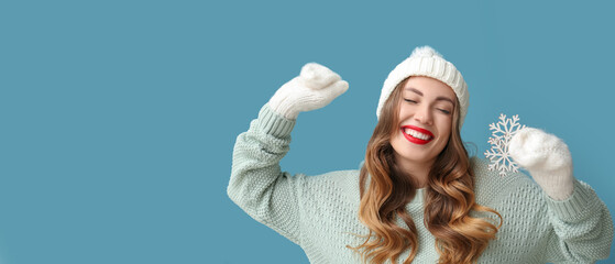 Beautiful happy young woman holding snowflake on light blue background with space for text