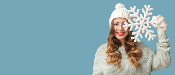 Beautiful smiling woman holding big snowflake on light blue background with space for text