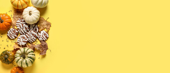 Halloween cookies,  pumpkins and autumn leaves on yellow background with space for text