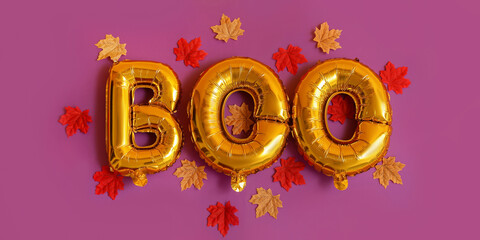 Word BOO made of balloons and autumn leaves on purple background