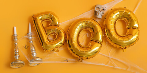 Word BOO made of balloons and Halloween decor on yellow background
