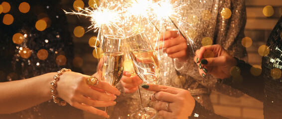 Women with glasses of champagne and Christmas sparklers, closeup