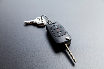 Car key on top of a black table with natural light. Key with buttons to lock and unlock the door. Car key concept. Door lock concept. Copy space.