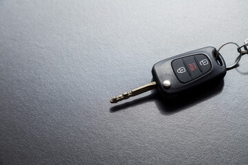 Car key on top of a black table with natural light. Key with buttons to lock and unlock the door. Car key concept. Door lock concept. Copy space.