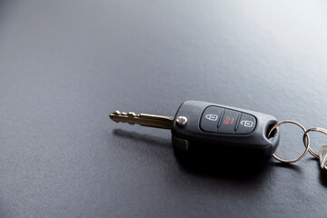 Car key on top of a black table with natural light. Key with buttons to lock and unlock the door. Car key concept. Door lock concept. Copy space.