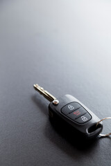 Car key on top of a black table with natural light. Key with buttons to lock and unlock the door. Car key concept. Door lock concept. Copy space.