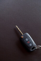 Car key on top of a black table with natural light. Key with buttons to lock and unlock the door. Car key concept. Door lock concept. Copy space.