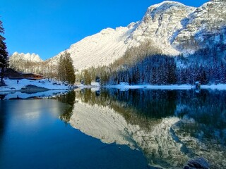 snow covered mountains and reflection in Lake Predil on Julian Alps in winter