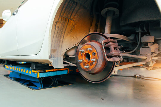 Rear disc brakes and calipers that remove the wheels of a car in the auto repair garage with sunlight