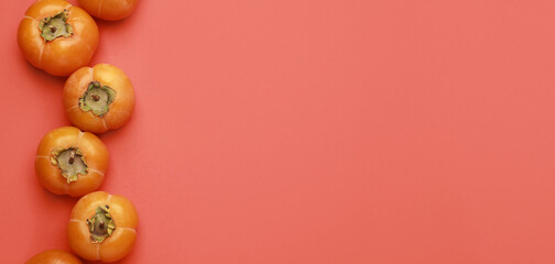 Ripe persimmons on red background with space for text, top view