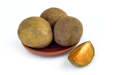 sapodilla fruit is in a small bowl and there are pieces of it of white background