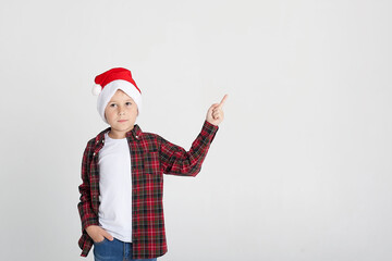 The charming seven year old boy in red Santa Claus cap smiles, having stretched hands up. The photo is executed by isolated.