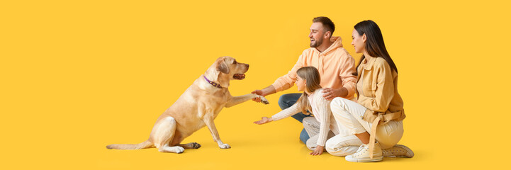 Happy family and cute Labrador dog on yellow background