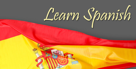 Text LEARN SPANISH and flag of Spain on grey background