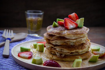 pancake strawberry avocado fruit and honey syrup sweeet dessert homemade and ready to eat on wood table.