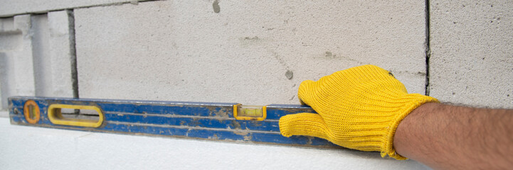 thermal insulation house. Worker hand with level measuring white rigid polyurethane foam sheet on...