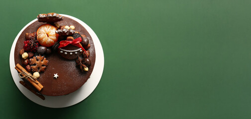 Tasty Christmas chocolate cake on green background with space for text, top view