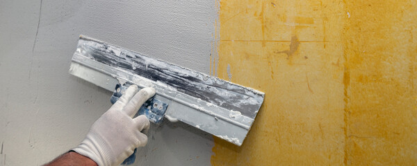 Plasterer applies plaster on the wall during repair and restoration work.