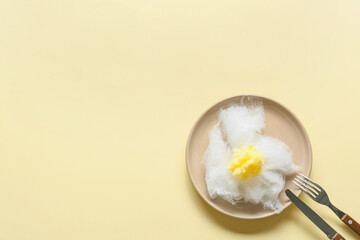 Composition with table setting and sweet cotton candy in shape of fried egg on yellow background