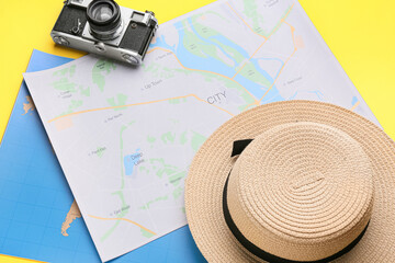 Fototapeta na wymiar World maps, photo camera and hat on yellow background