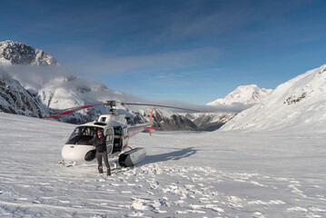 Man posing in front of a helicopter on a sunny morning along the Tasman Glacier in the Southern...