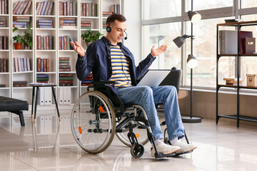 Young man in wheelchair using laptop at home