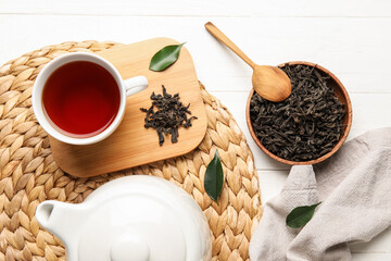Composition with dry tea leaves and hot beverage on white wooden background