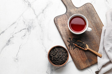 Composition with dry tea leaves and cup of hot beverage on marble background