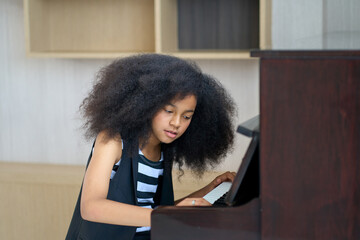 Teenage girl is playng piano for free hobby time in home living room
