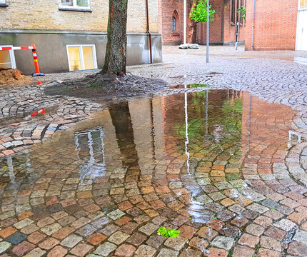 Big rain puddle on an old cobbled street in a Danish city after massive rain in the fall