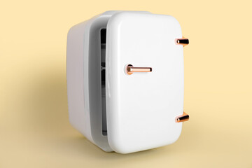 Small cosmetic refrigerator on color background