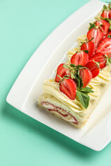 Plate with delicious strawberry roll cake on color background, closeup