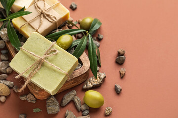 Board with olive soap bars and stones on color background, closeup
