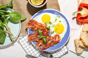 Plate of tasty fried eggs with bacon on table
