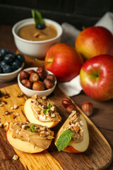 Board of fresh apple wedges with nut butter on wooden table, closeup