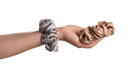 Female hand with silk scrunchies on white background