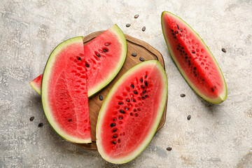 Fototapeta na wymiar Cutting board with slices of watermelon on grunge background