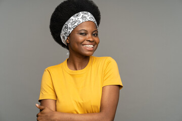 Black female wearing headband on kinky hair enjoys performing on small sketch and showing positive emotions against grey studio wall. Young African American woman wants to become actress in main cast