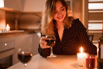 Beautiful woman in a black dress having a glass of wine, on date with partner. Indoors lifestyle...